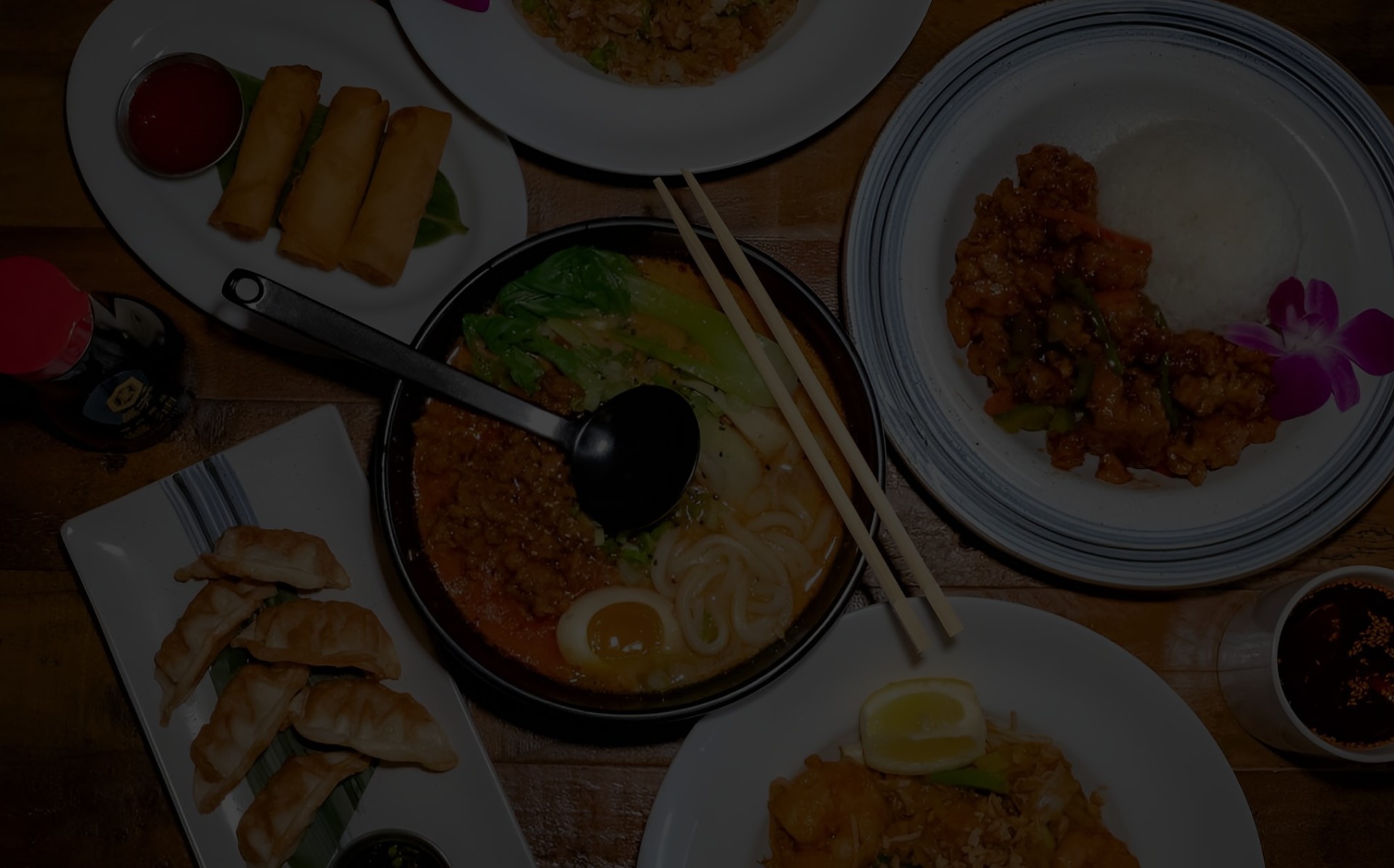 107 Taste, an Asian restaurant in Miami. A large bowl of ramen noodles or tantanmen with broth, minced meat, bok choy vegetables, and a hard-boiled egg, served with chopsticks and a ladle on the side.